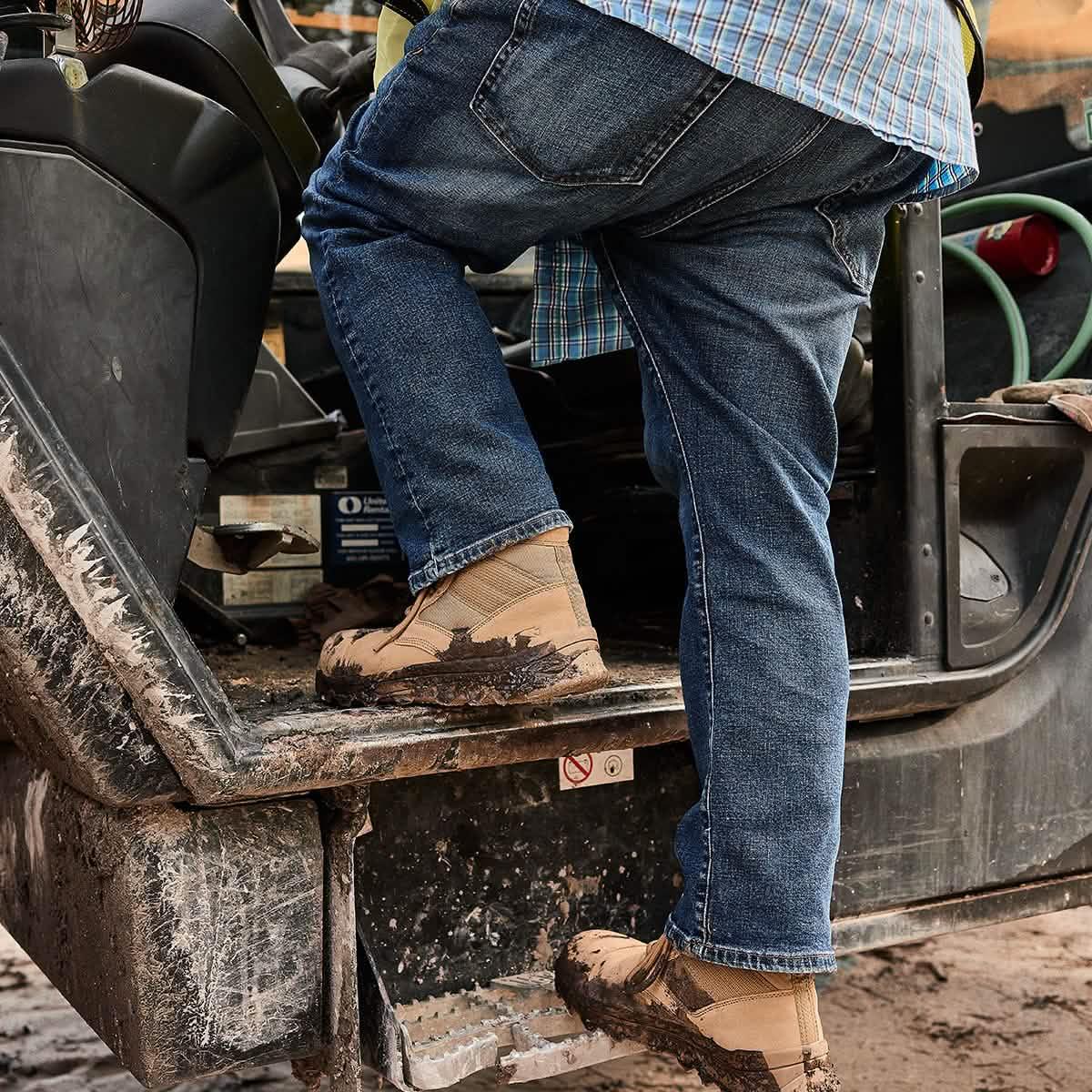 Person in jeans and tan GORUCK boots with mud climbing into rugged utility vehicle
