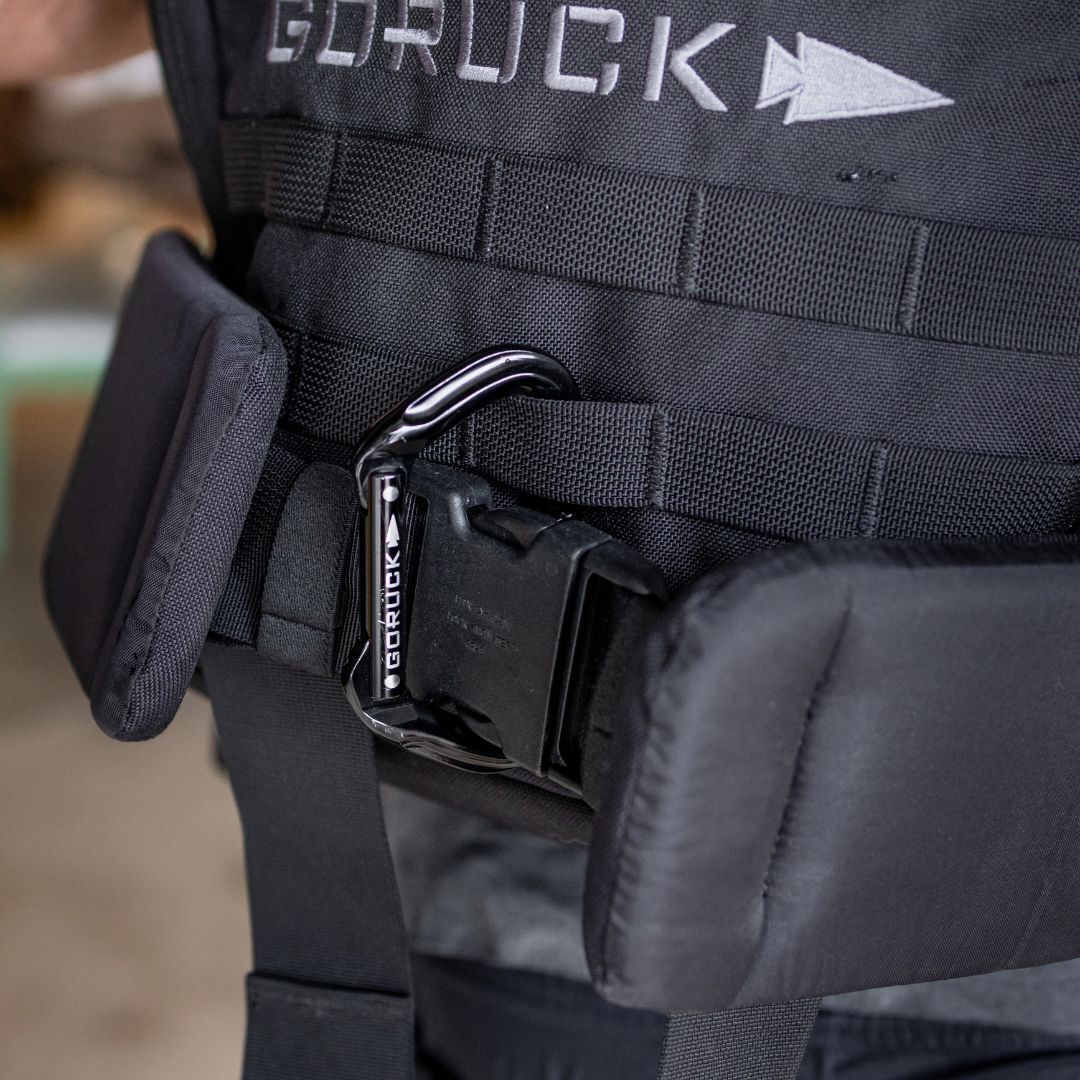 Black GORUCK tactical vest secured with a branded aluminum carabiner.