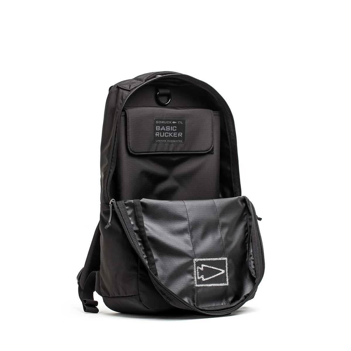 Black Basic Rucker® backpack with an open front pocket, displaying a patch labeled Basic Rucker® and a stitched arrow design.