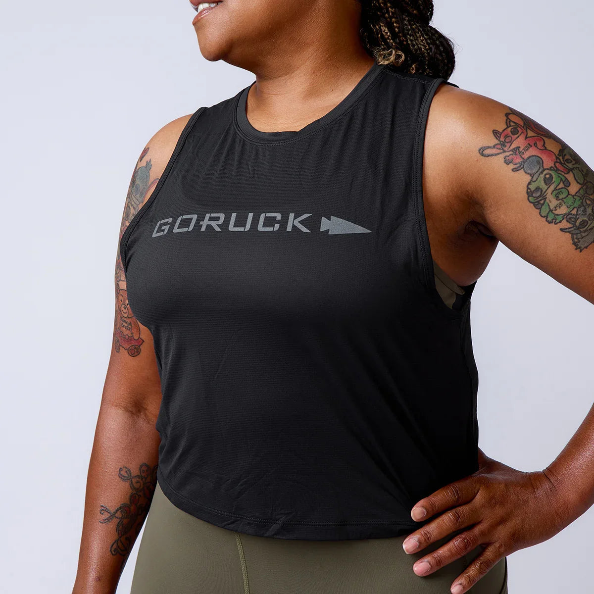 GORUCK women's sleeveless black tank top with logo, worn by model with arm tattoos