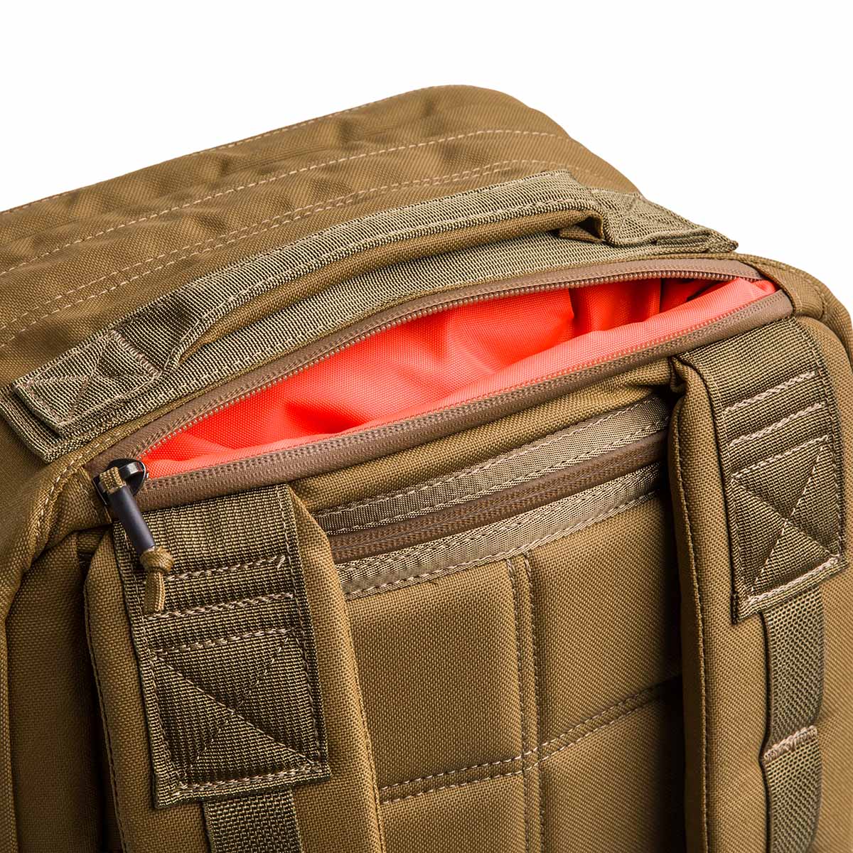 Close-up of the tan GR2 - Cordura ruck featuring padded straps and an open zipper that reveals a bright orange interior, making it an ideal carry-on travel bag.