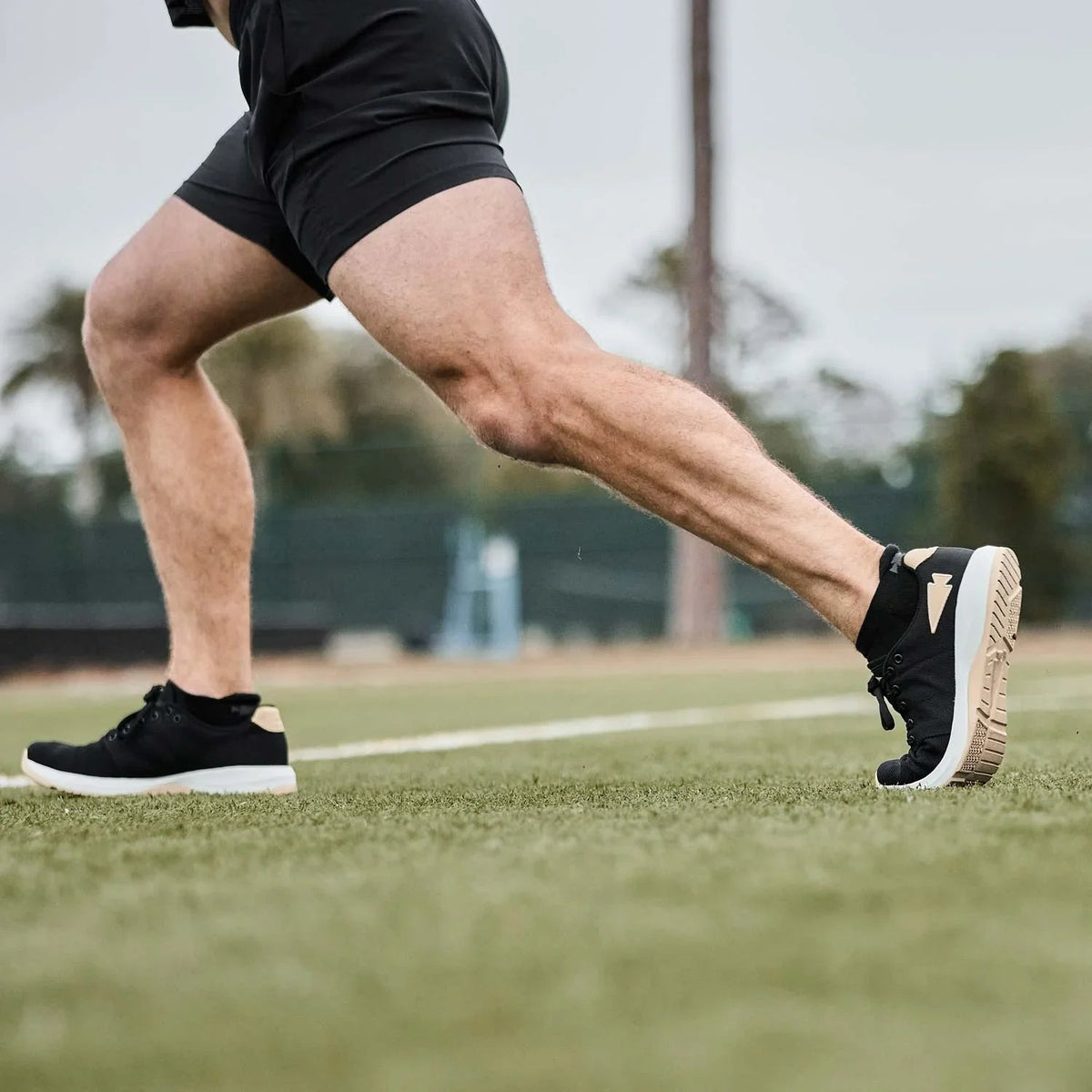 Man running on grass in GORUCK black athletic shoes and shorts, outdoor fitness training