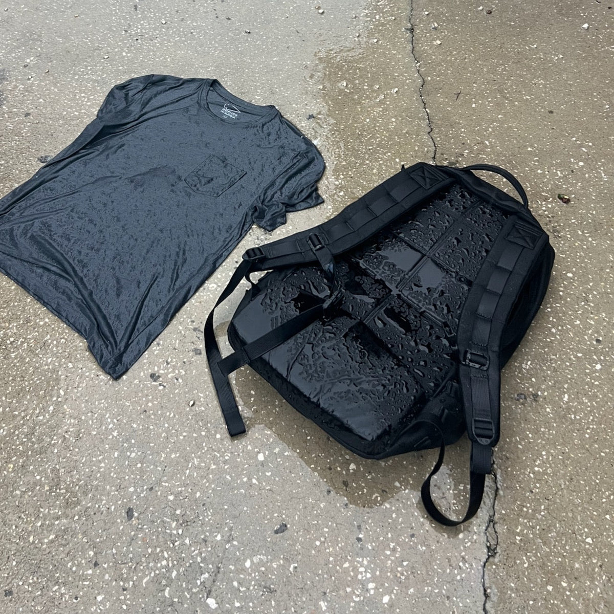 A wet gray t-shirt and a comfortable rucksack lying on a damp concrete surface after a distance rucking event.