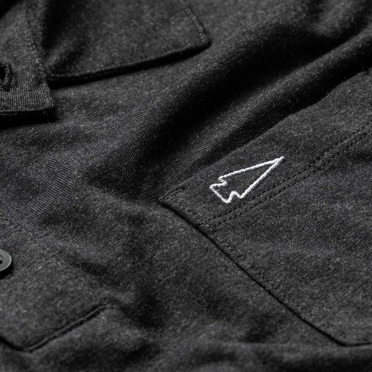 GORUCK men's black triblend polo with pocket and white spearhead embroidery close-up