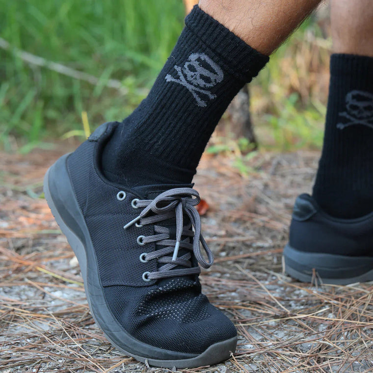 GORUCK black rucking shoes and skull socks on outdoor trail with pine needles