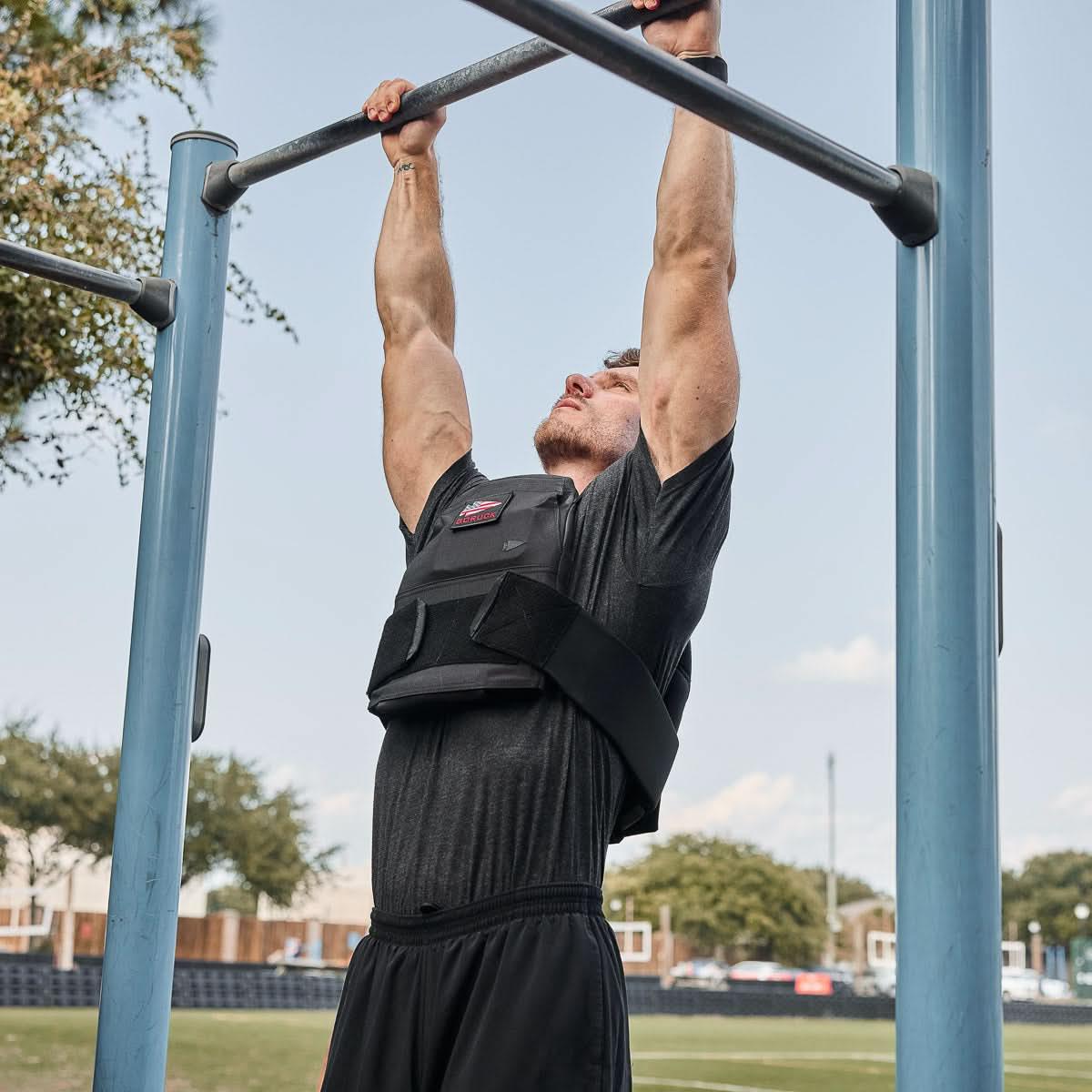 Man in GORUCK weighted vest doing pull-ups outdoors on blue fitness bar