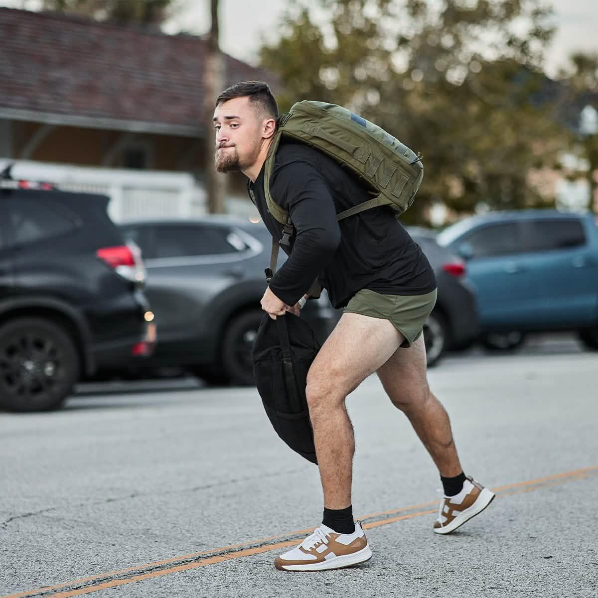Man in GORUCK ToughMesh black long sleeve, olive shorts, rucking outdoors with backpack