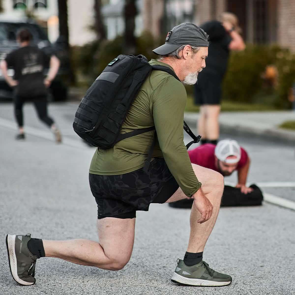 Man wearing a GORUCK backpack and ToughMesh long sleeve shirt doing outdoor rucking exercise.