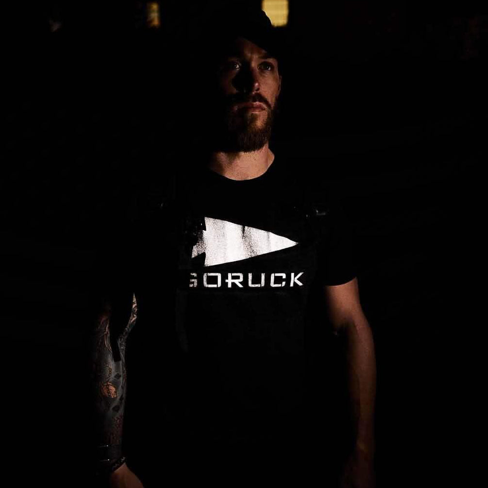 Man wearing black GORUCK reflective tee in low light, showing rucking gear logo.