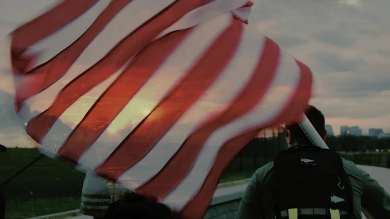 A person stands near an American flag at sunset