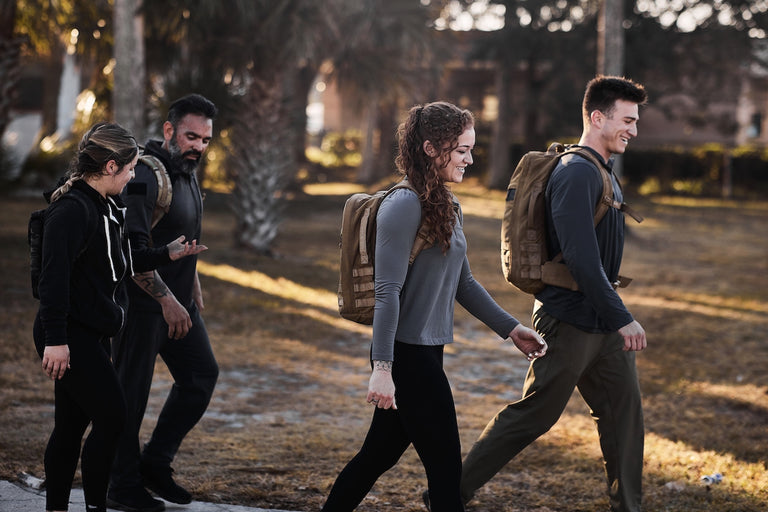 Two men and two women wearing backpacks hike together outdoors.